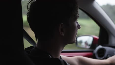 Young-man-driving-a-car-in-daytime,-close-up