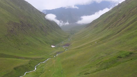 Aerial-shot-of-river-and-valley-in-the-middle-of-mountains-with-cloud-and-fog-caucasian-mountains