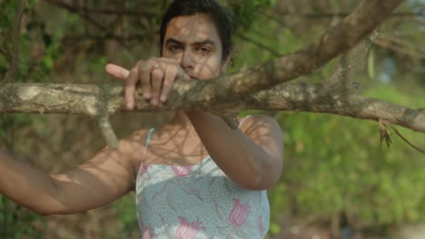 A-young-indian-woman-is-hanging-from-a-tree-branch