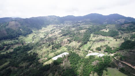 Backward-aerial-view-of-range-of-green-hills-with-mountain-plants-on-them-during-daytime