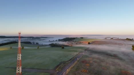 A-road-leads-through-a-misty-rural-landscape-in-the-early-morning-hours