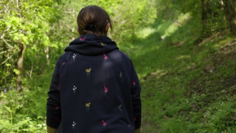 Lady-in-Jumper-Walking-Up-Hill-on-Hot-Day-in-the-Woods---Slow-Motion-Tracking-Shot