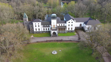 Aerial-View-of-Historic-Manor-with-Surrounding-Trees