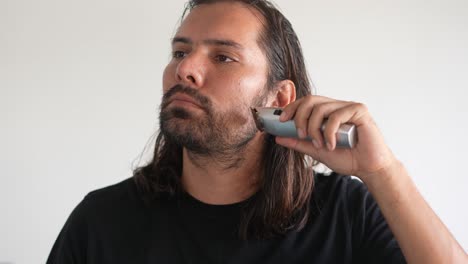 Latino-man-trimming-beard-and-mustache-with-electric-razor,-Safety-razor,-man-with-long-hair