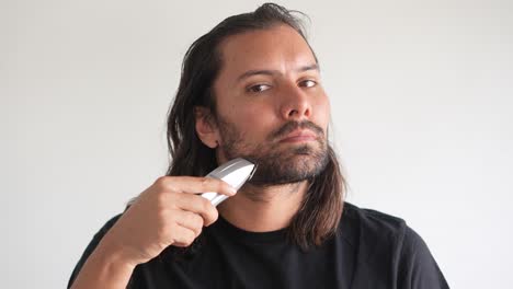 Hombre-Latino-Recortando-Barba-Y-Bigote-Con-Afeitadora-Eléctrica,-Cera-Para-Barba