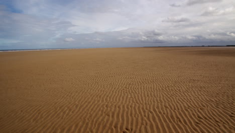 Toma-Extra-Amplia-De-Ondulaciones-En-Una-Playa-Plana-Con-Nubes-De-Tormenta-En-El-Tercio-Superior