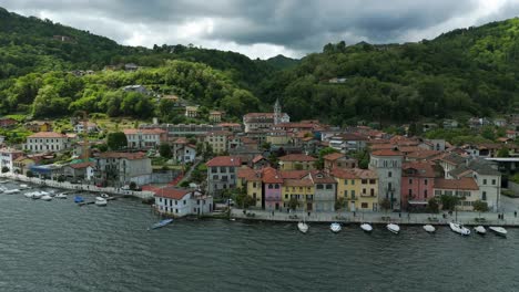 Una-Pintoresca-Ciudad-Costera-Con-Coloridos-Edificios-Que-Bordean-Un-Tranquilo-Lago,-Respaldado-Por-Verdes-Colinas-Y-Cielos-Nublados