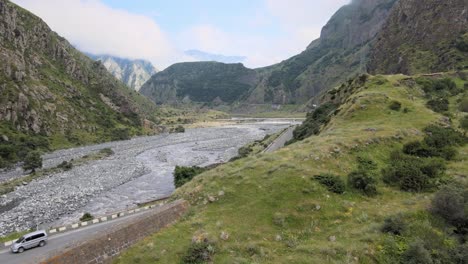 Aerial-shot-of-river-in-the-middle-of-mountains-sky-and-cloud-in-the-background