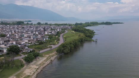 Aerial-footage-of-a-small-village-settlement-next-to-the-Haishe-Ecological-Park-in-Dali,-Yunnan-Province-in-China