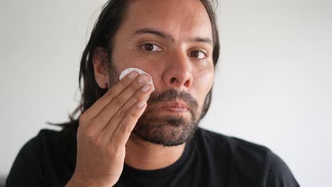 skincare,-face-cleaning,-skin-care,-Latino-man-wiping-his-face-with-cotton-swab