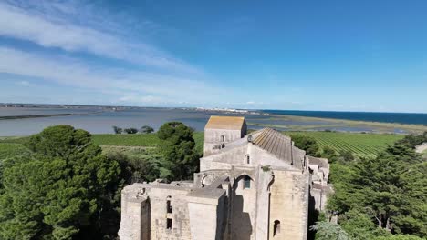 Romanesque-Maguelone-cathedral-from-the12th-century-on-a-volcanic-island-near-the-Mediterranean-coast-of-France,-Aerial-flyover-shot