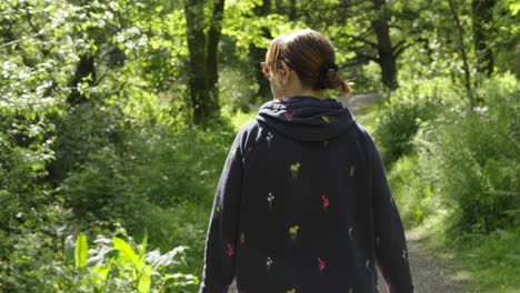 Mujer-Caminando-Por-Un-Sendero-Forestal-Natural-Con-Gafas-De-Sol-En-Un-Día-Caluroso-Y-Soleado---Toma-De-Seguimiento-En-Cámara-Lenta