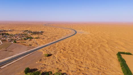 Aerial-of-a-road-winding-through-the-desolate-desert-landscape-of-Tengger-Desert,-Inner-Mongolia-Autonomous-Region,-China,-the-concept-of-isolation,-natural-beauty