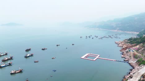 Vista-Aérea-De-La-Costa-Del-Mar-Con-Barcos-Flotando-En-El-Agua-Cerca-De-La-Ciudad-De-Xiapu,-Provincia-De-Fujian,-China