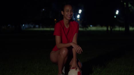 A-young-girl-wearing-a-bikini-holds-a-football-in-her-hand-under-the-night-sky