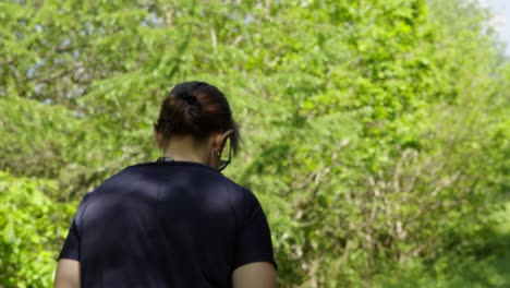 Mittlere-Kamerafahrt-Einer-Dame,-Die-Im-Wald-Entlang-Eines-Parkwaldweges-Wandert