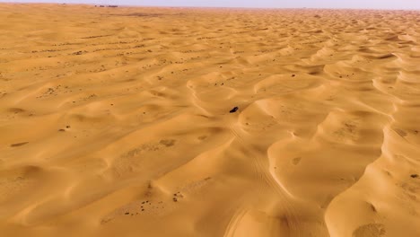 Aerial-of-a-pickup-truck-moving-along-the-sandy-and-desolate-dunes-of-Tengger-Desert-in-Inner-Mongolia-Autonomous-Region,-China