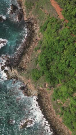 Vertical-aerial-view-showcasing-the-cliffs-and-rocks-of-Punta-Cometa-in-Mazunte,-Oaxaca