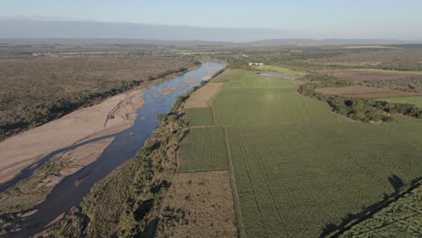 Drone-footage-reveals-contrasting-sugarcane-and-pepper-farms,-divided-by-a-seasonal-river,-bordering-Kruger-National-Park