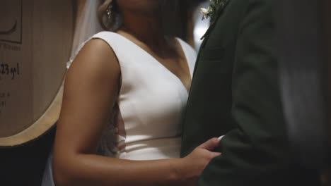 Bride-and-groom-kiss-passionately-in-cellar-with-barrels