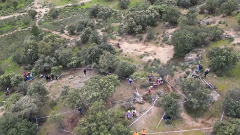 Drohnenflug,-Der-Einen-Abschnitt-Einer-Motocross-Rennstrecke-Mit-Menschen-Visualisiert,-Die-Das-Rennen-Beobachten-Und-Daran-Teilnehmen,-Wobei-Ein-Motorrad-Auf-Der-Strecke-Und-Mehrere-Außerhalb-Des-Rennens-Unterwegs-Sind