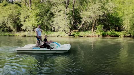 Three-male-holiday-friends-enjoy-pedalo-boat-trip-adventure-on-river