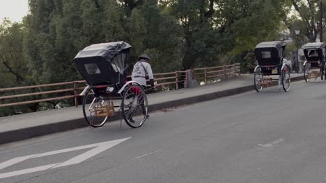 Three-Rickshaws-being-pulled-by-men,-carrying-passengers-down-the-Street