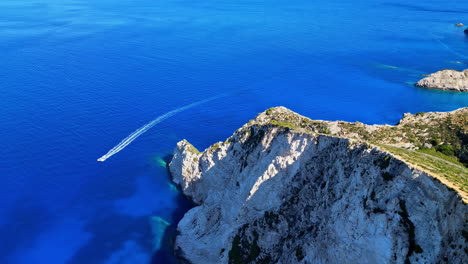 Un-Barco-Se-Desliza-Por-Aguas-Cristalinas-Cerca-De-Un-Impresionante-Acantilado-En-Navagio,-Grecia