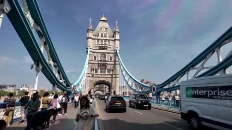 Front-view-of-iconic-Tower-bridge-in-London,-UK-with-locals-and-tourists-passing-by-it-during-daytime