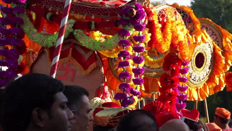Palanquin-chair-adorned-with-flowers-and-Hindu-swastika-carried-at-religious-festival