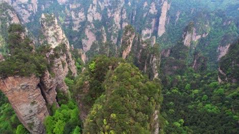 Drones-Hacia-Atrás-Volando-Sobre-Un-Frondoso-Bosque-En-La-Aldea-De-Huangshi-En-El-Parque-Forestal-Nacional-De-Zhangjiajie,-China