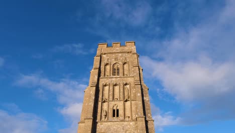 Looking-up-at-St-Michael's-Tower-at-the-summit-of-The-Tor-against-a-vivid-blue-sky-on-the-Somerset-Levels-in-Glastonbury,-England-UK