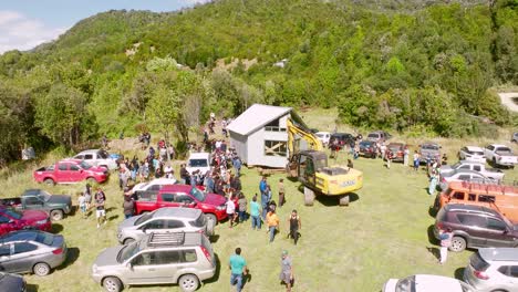 Luftaufnahme-Von-Oben,-Die-Ein-Lebhaftes-Treffen-Der-Gemeinde-Im-Freien-Mit-Geparkten-Autos-Und-Menschen-Einfängt,-Die-Sich-Um-Ein-Kleines-Gebäude-Versammeln