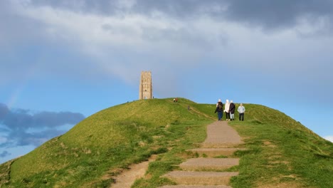 People-walking-up-and-down-the-steep-footpath-at-popular-tourism-attraction-of-The-Tor-in-Glastonbury,-Somerset,-England-UK