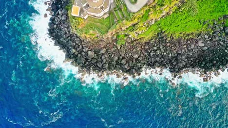 Topdown-view-of-Arnel-Lighthouse-on-turquoise-seashore-cliff-in-São-Miguel-Island,-Azores