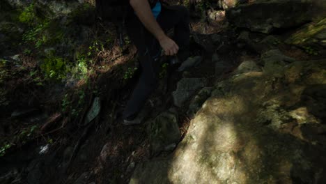 Tracking-shot-of-man-with-backpack-and-camera-climbing-hiking-trail-through-forest