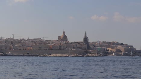 View-of-Malta's-coastline-with-the-Basilica-Sanctuary-of-Our-Lady-of-Mount-Carmel-dome-in-the-background