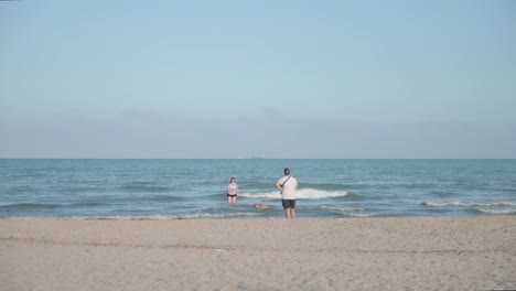 Family-playing-with-their-dog-on-the-beach-on-a-sunny-day