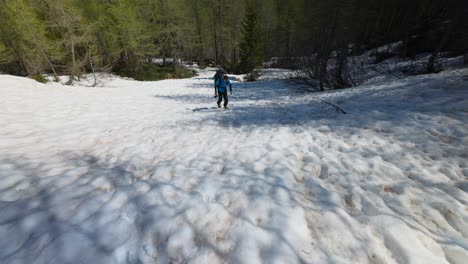 A-man-hikes-up-snowy-mountain-slope-with-backpack-and-camera