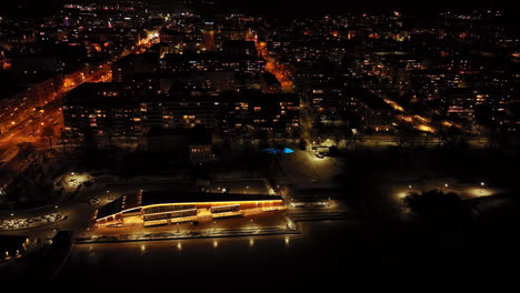 Aerial-tracking-shot-in-front-of-the-illuminated-Vaasa-city,-night-in-Finland