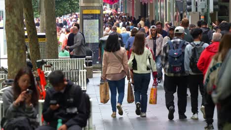 Downtown-Melbourne's-streets-are-packed-with-people-during-peak-hours,-pedestrians-surge-through-the-bustling-city-center,-filling-the-sidewalks-and-crossing-streets-in-every-direction