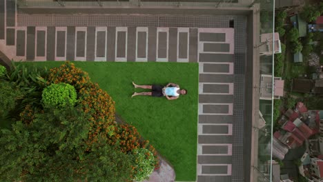 Top-down-aerial-view-ascending-over-a-person-lying-on-the-rooftop-of-a-high-rise-building-in-Hanoi,-Vietnam,-illustrating-the-concept-of-urban-contemplation