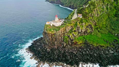 Drone-flyover-toward-Scenic-Arnel-Lighthouse-on-top-of-rugged-cliff-over-the-Atlantic-Ocean,-Azores