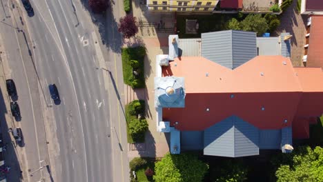 Drone-flies-over-church,-its-roof,-highway,-and-houses-and-trees-behind-it-in-Slovenska-Bistrica,-Slovenia