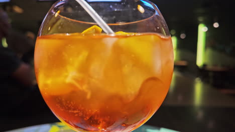 Ein-Leuchtend-Orangefarbener-Cocktail-Mit-Strohhalm-Auf-Einer-Neonbeleuchteten-Bowlingbahn