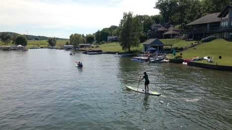 People-Ride-Paddle-Boards-Past-Lakefront-Houses-in-Pennsylvania,-U