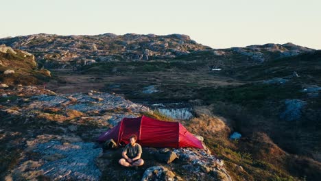 Male-Camper-Sitting-Outside-Camping-Tent-At-Sunset-In-Indre-Fosen,-Norway