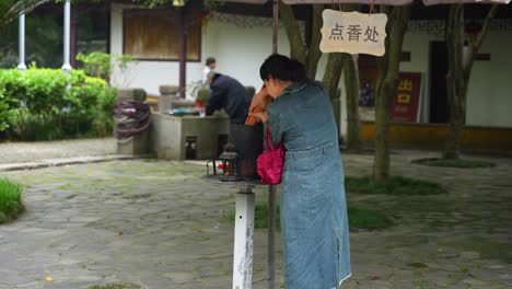 Chinesin-Zündet-Räucherstäbchen-Im-Tempelhof-An