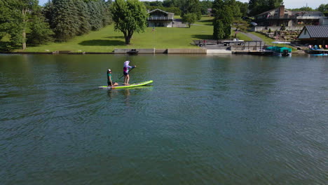 Filas-De-Niña-En-Paddle-Board-Con-Mujer-Montando