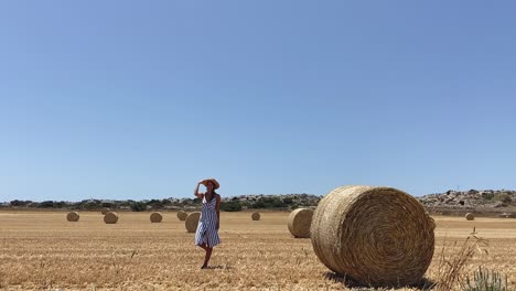 Girl-throwing-hat-to-the-air-in-the-roller-bale-in-the-hay-fields